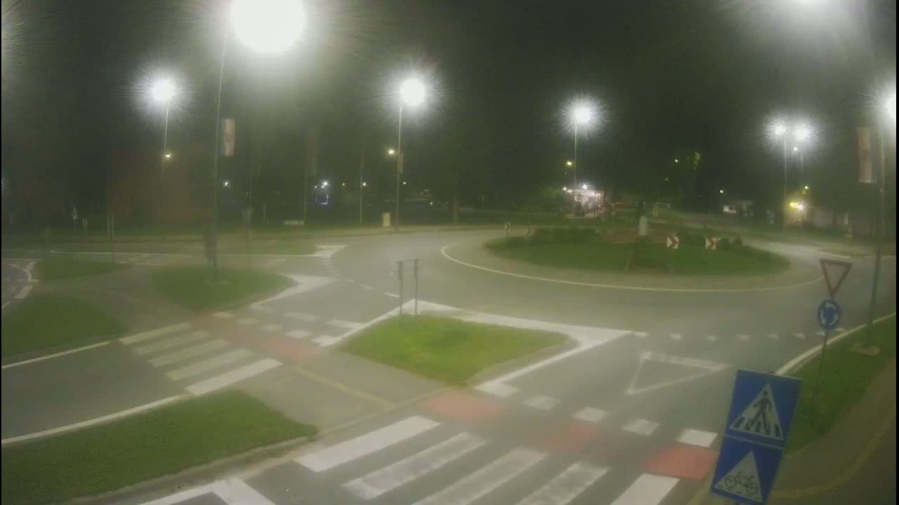 A nighttime view of a roundabout with pedestrian crossings, illuminated by streetlights.