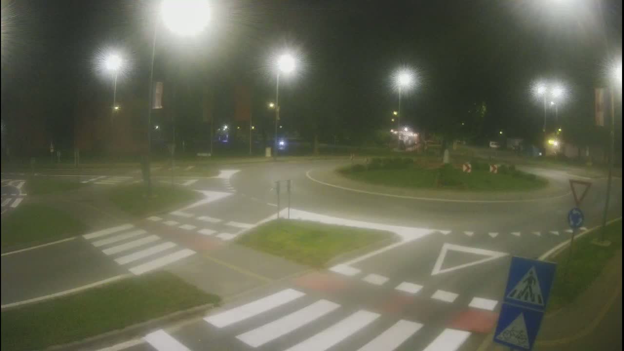 A nighttime view of a roundabout with pedestrian crosswalks and streetlights illuminating the scene.