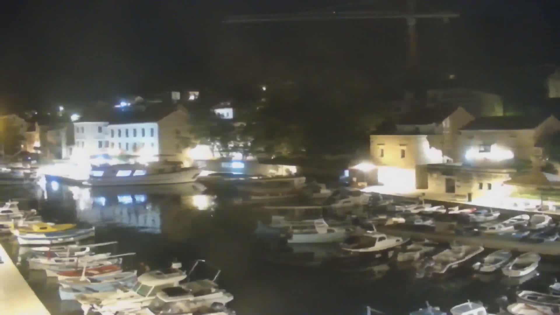 A nighttime view of a harbor filled with boats moored alongside illuminated buildings.