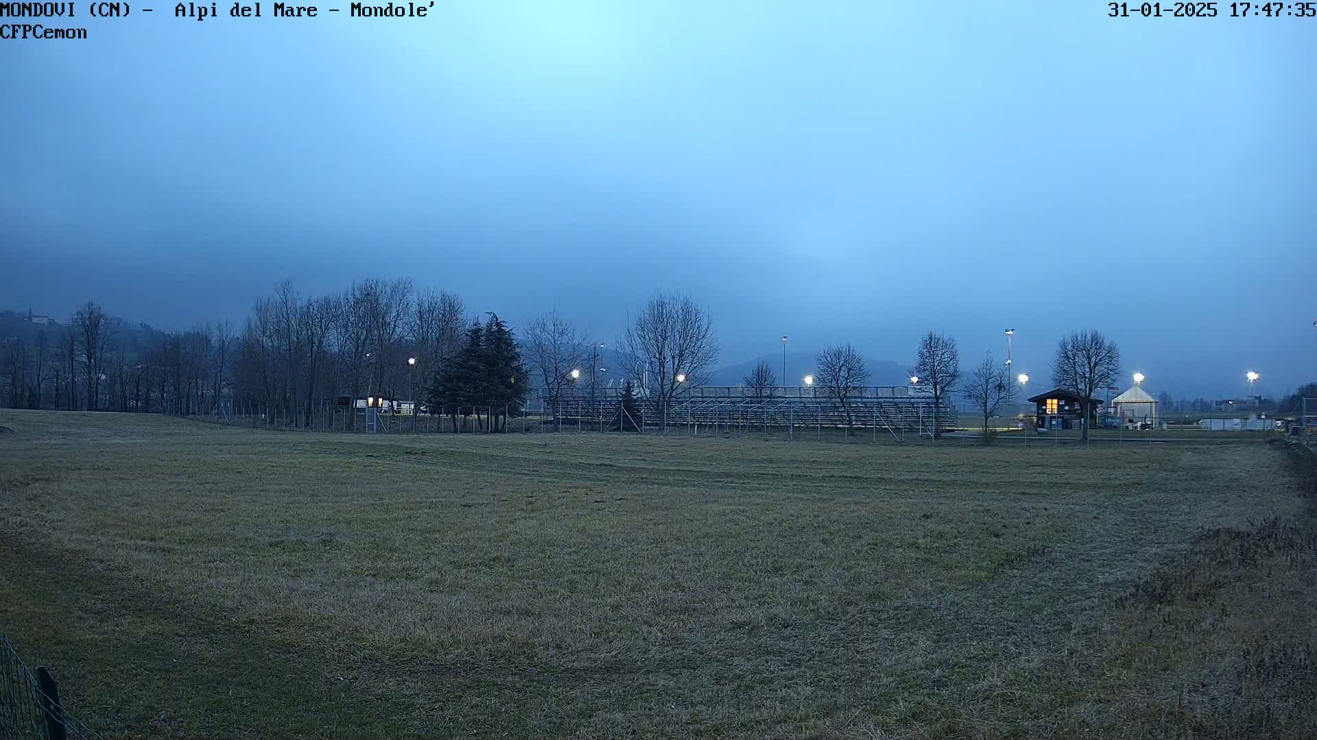 A field with bleachers and a small building is visible under a twilight sky.