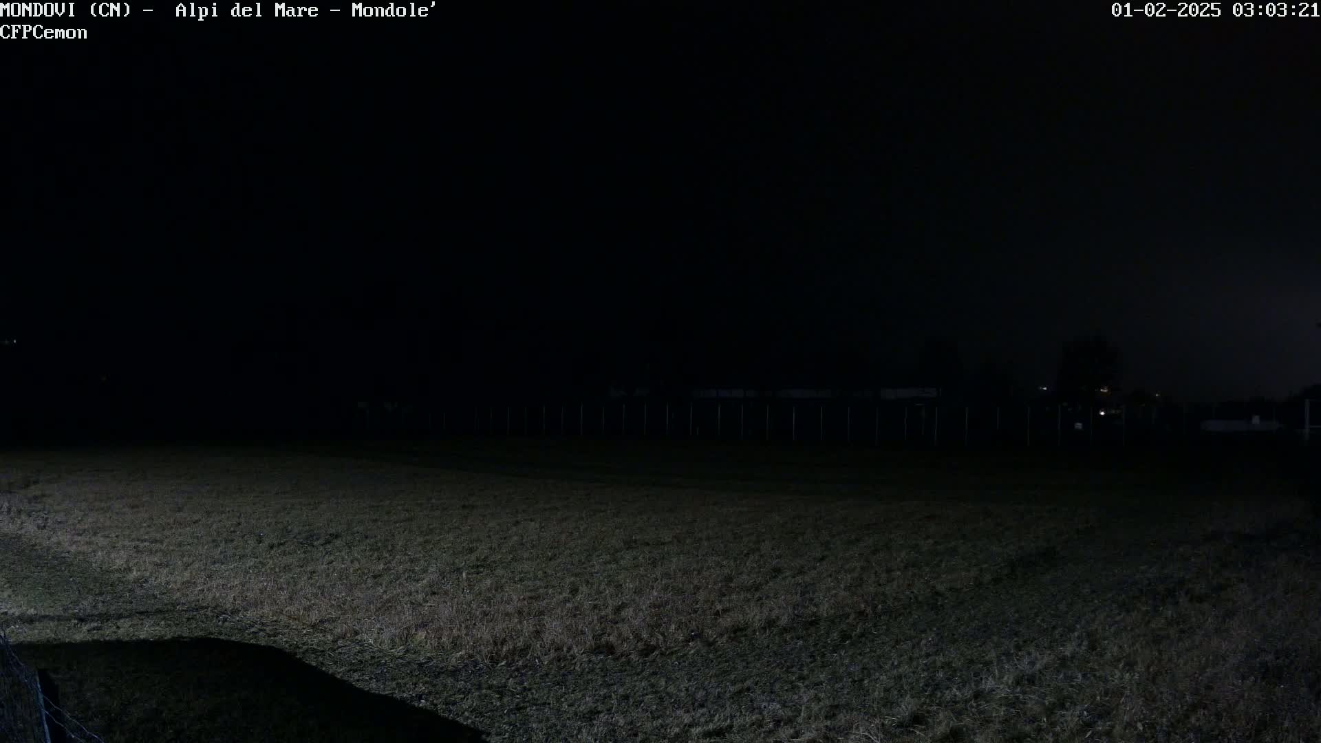 A dark, grassy field is visible at night under a mostly clear sky.
