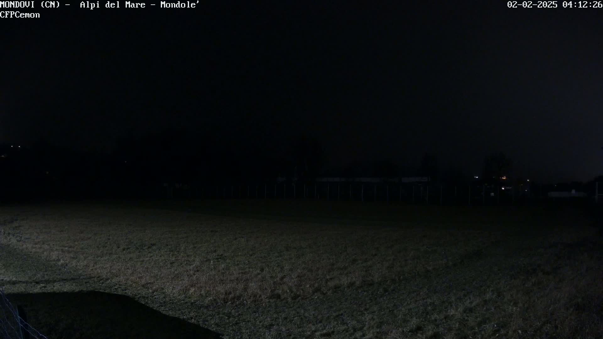 A dark, grassy field is visible at night, under a completely overcast sky.