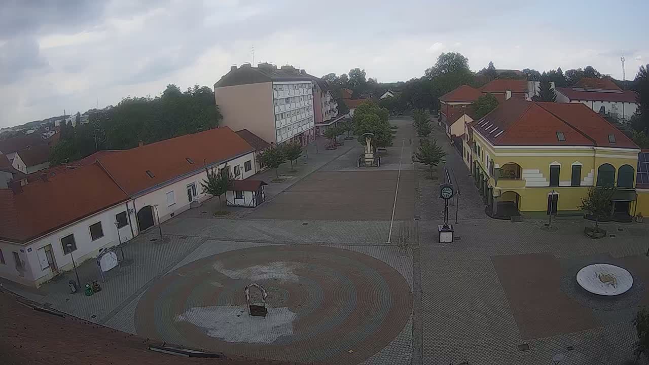 An overcast day reveals a town square with low buildings and a circular paved area in the center.