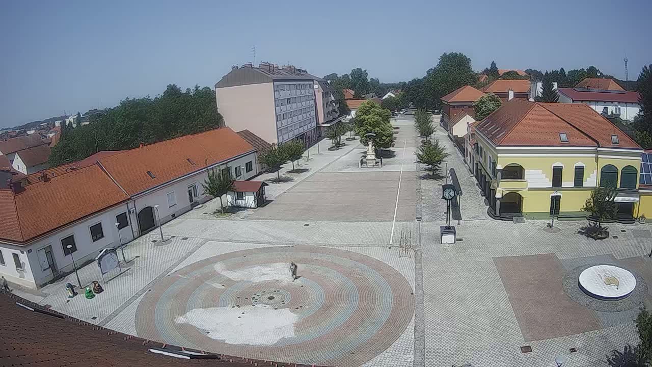 A large town square with low buildings and a circular paved design in the center, on a sunny day.