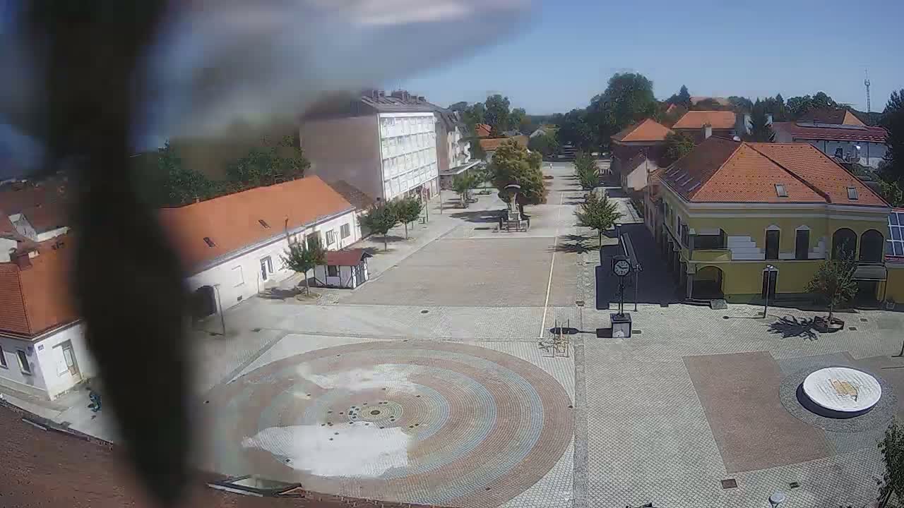 A town square with several buildings surrounding a circular paved area on a sunny day.