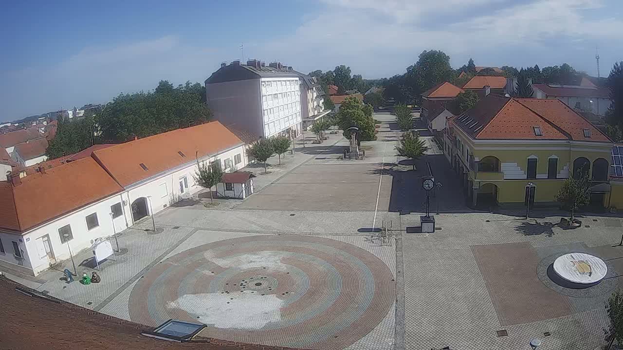 A town square with buildings surrounding it, under a clear sunny sky.