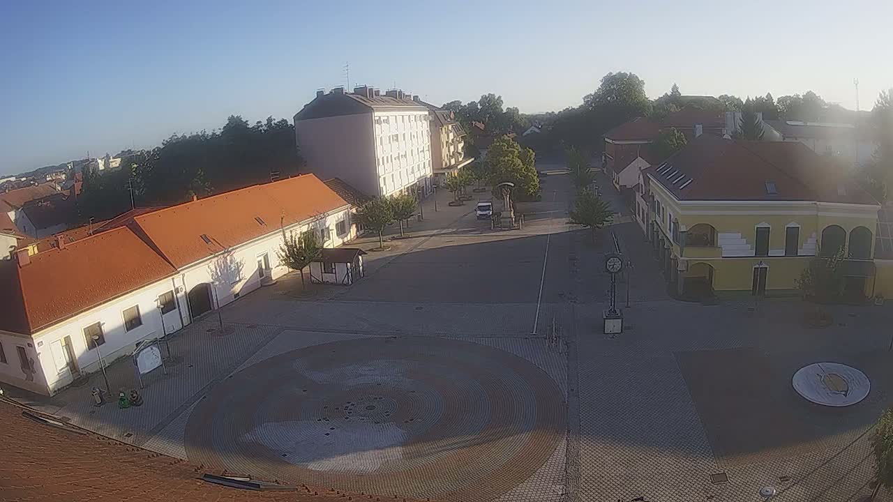 A town square with buildings surrounding it, under a clear sunny sky.
