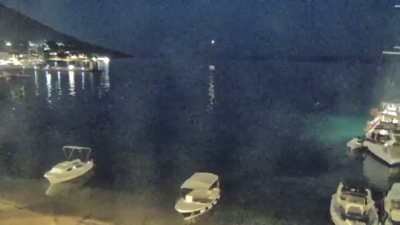Several small boats are moored at a waterfront at night under a dark, clear sky.