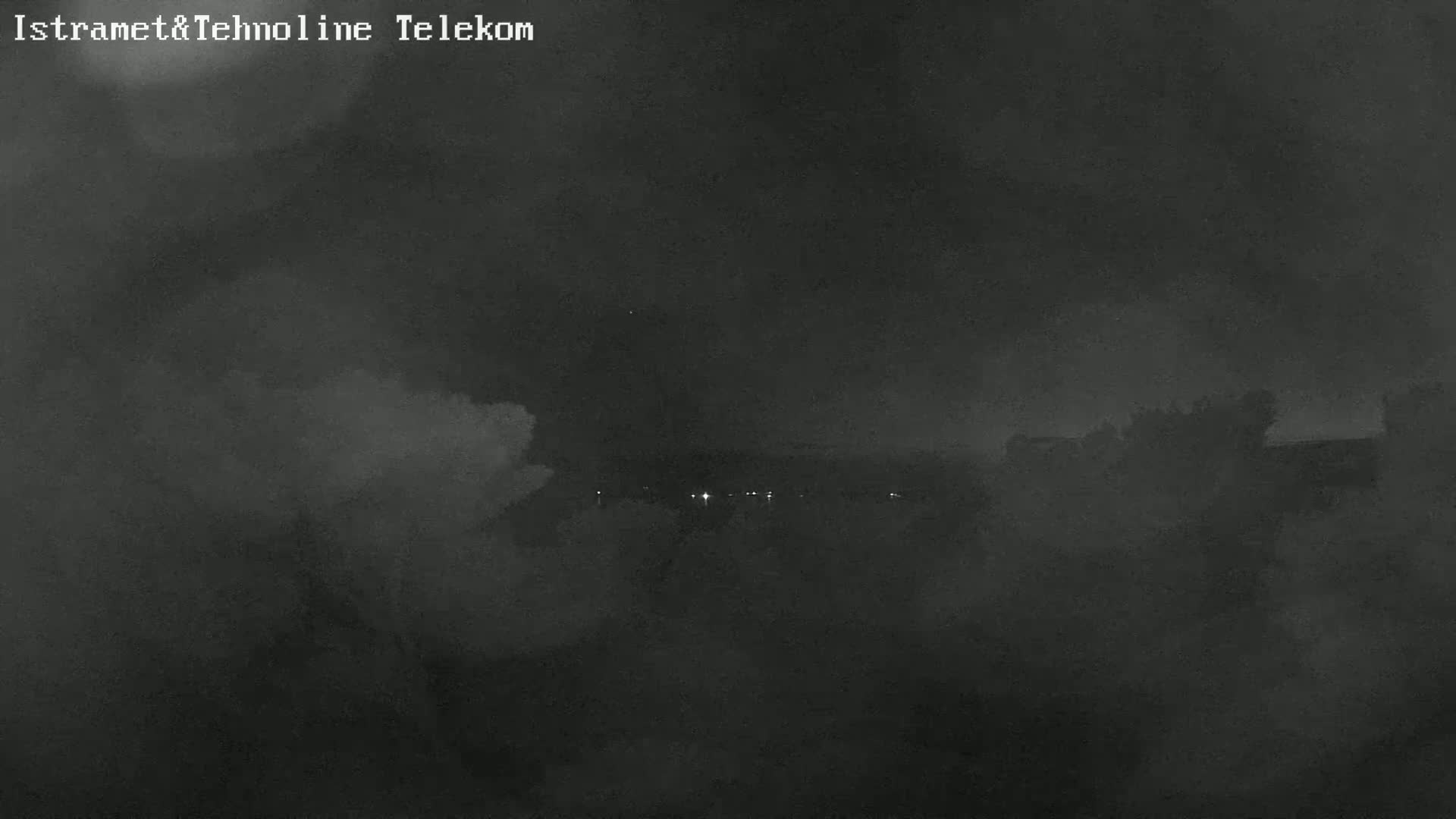 A nighttime, hazy, or foggy view shows a dark landscape with a few distant lights.