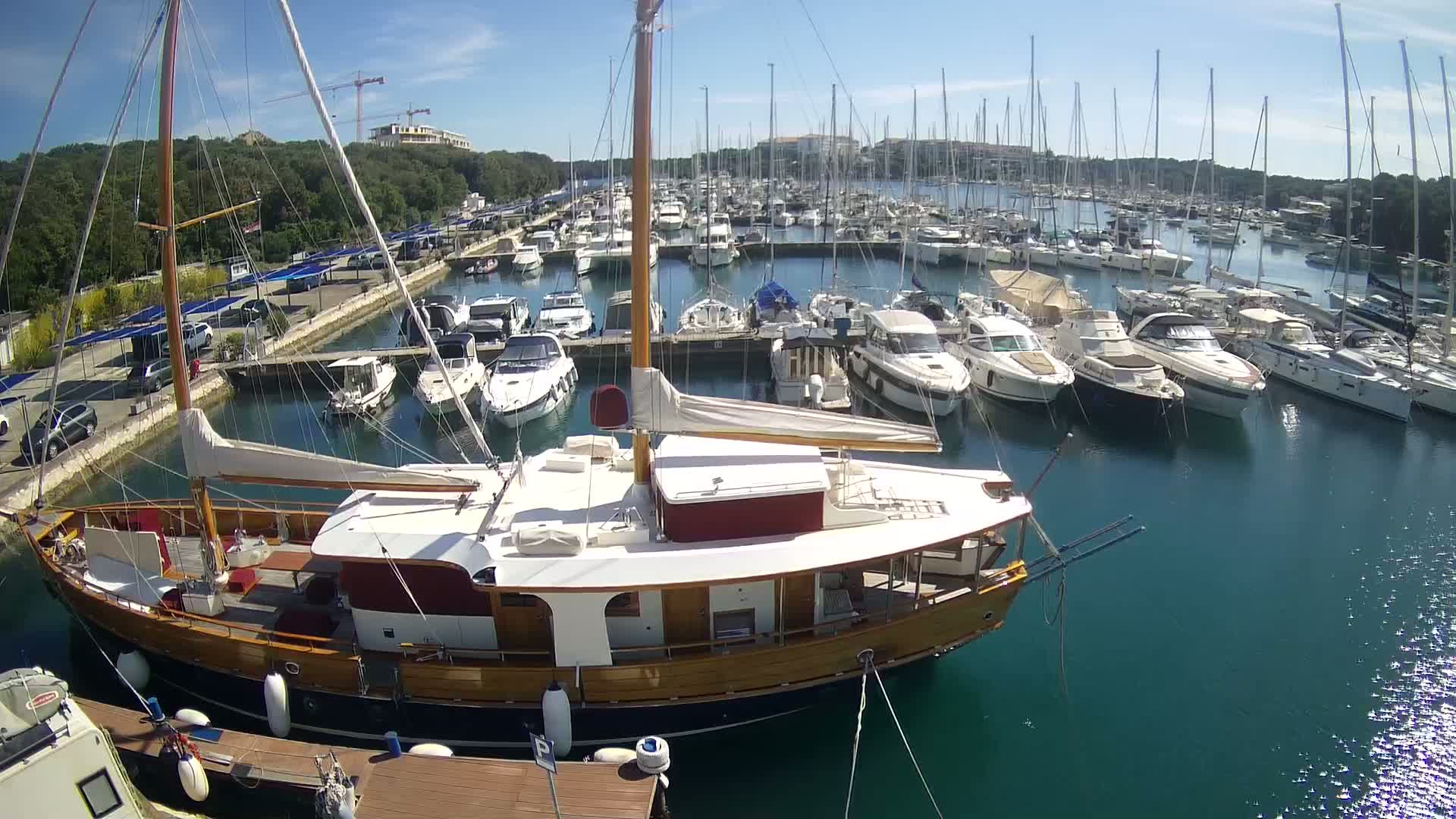 A marina filled with numerous sailboats and motorboats on a sunny day.