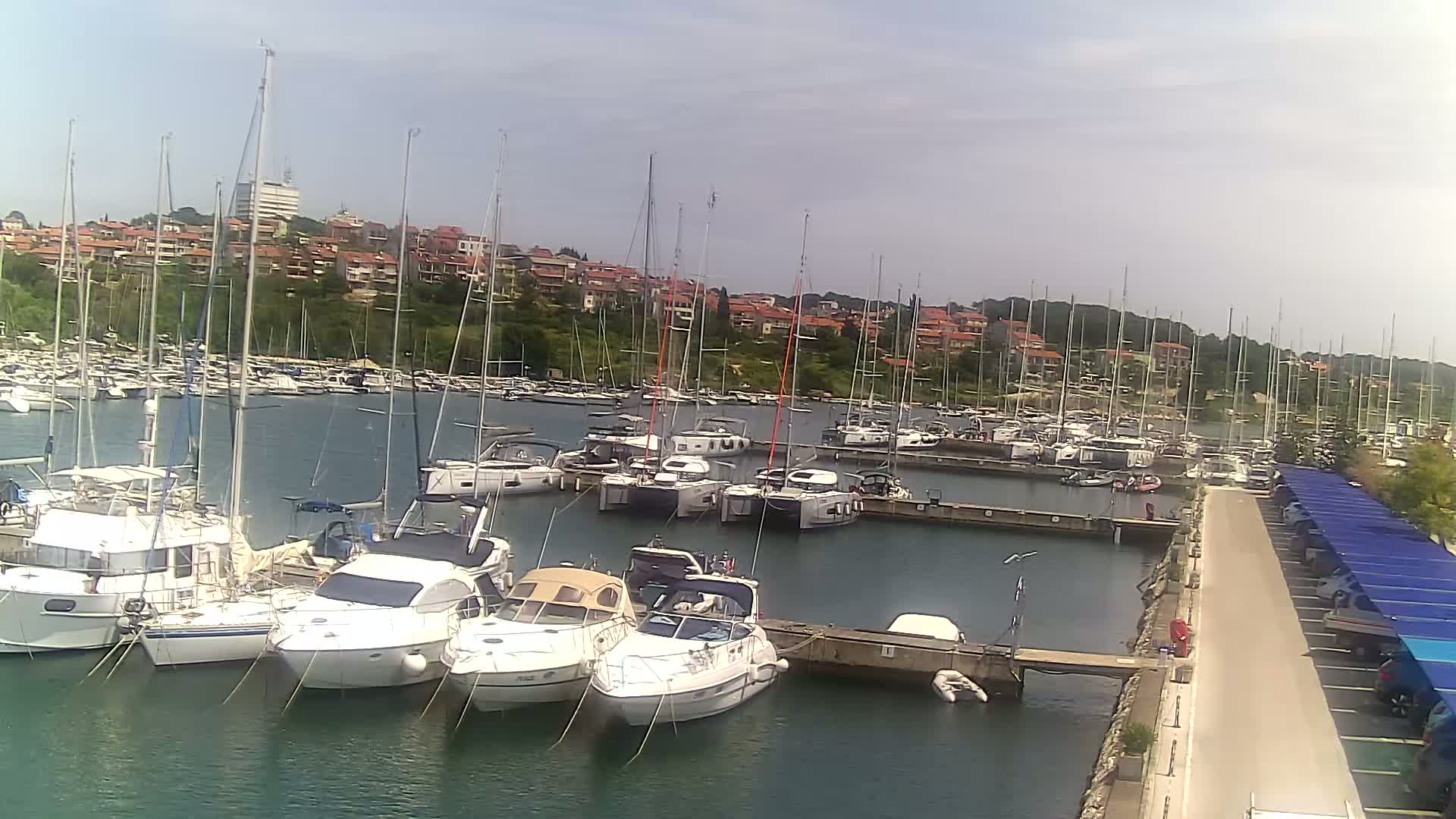A marina filled with sailboats and motorboats under a mostly sunny sky.