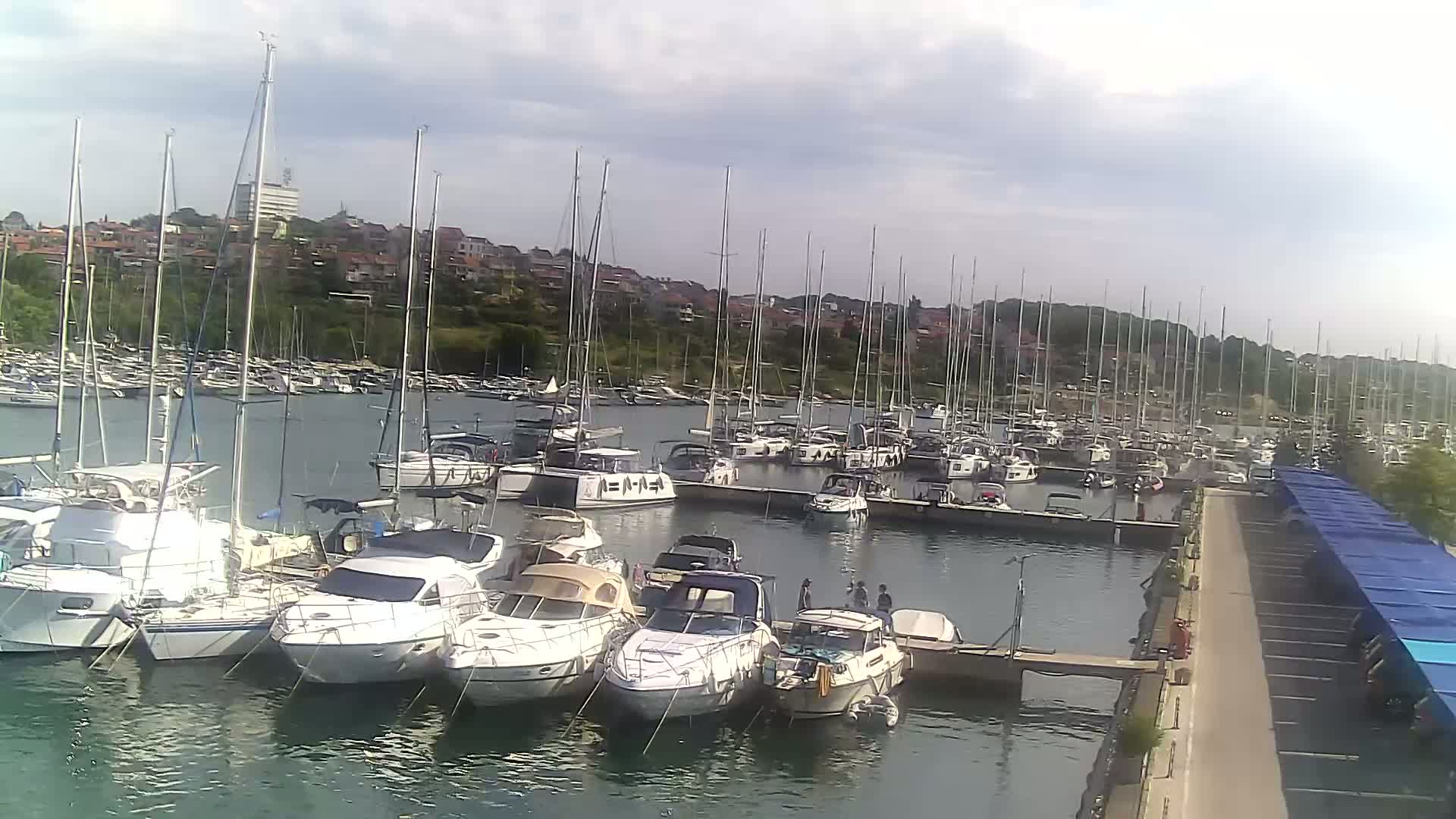 A marina filled with numerous sailboats and motorboats under a partly cloudy sky.