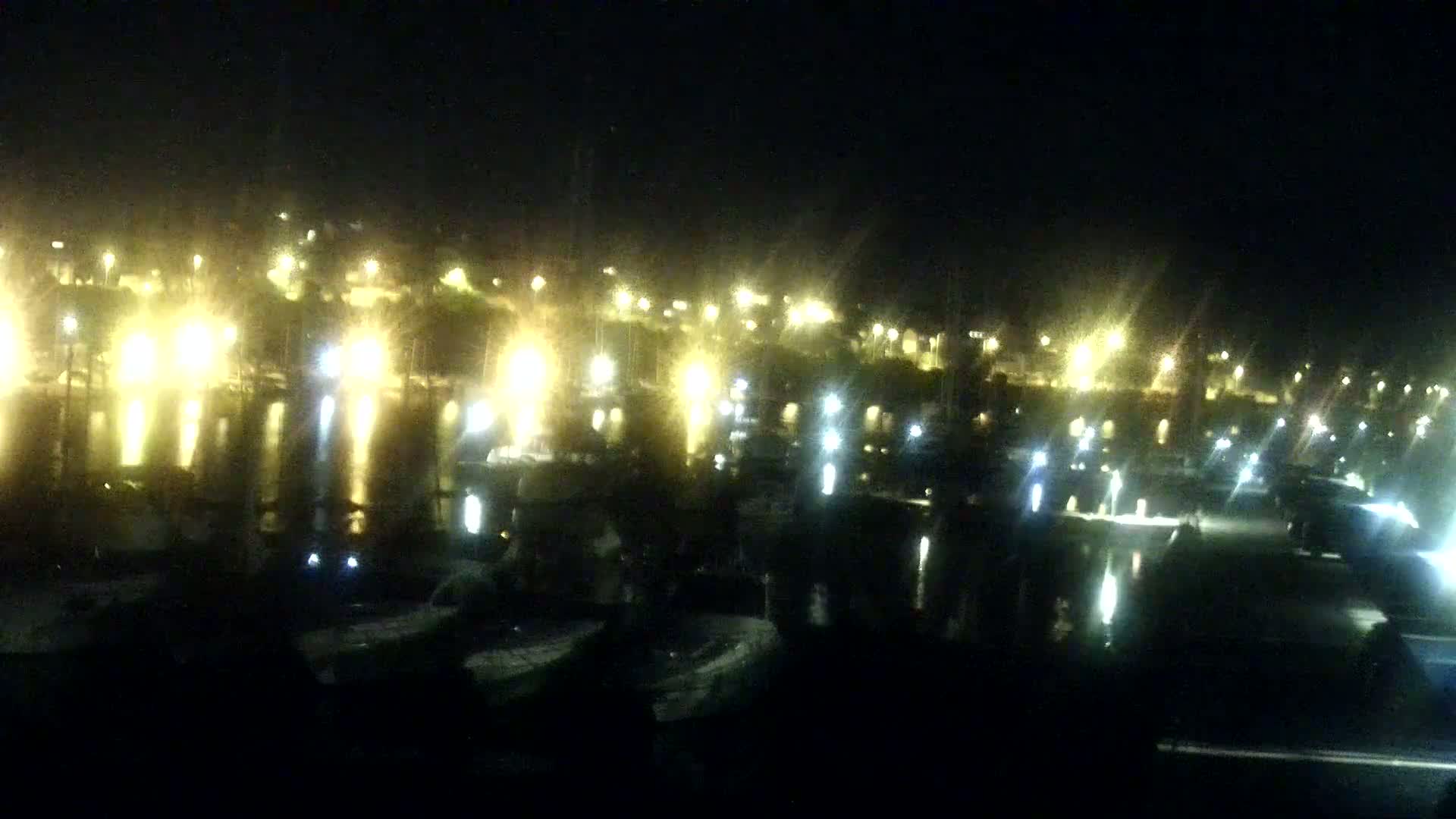 A marina filled with numerous sailboats and motorboats under a partly cloudy sky.