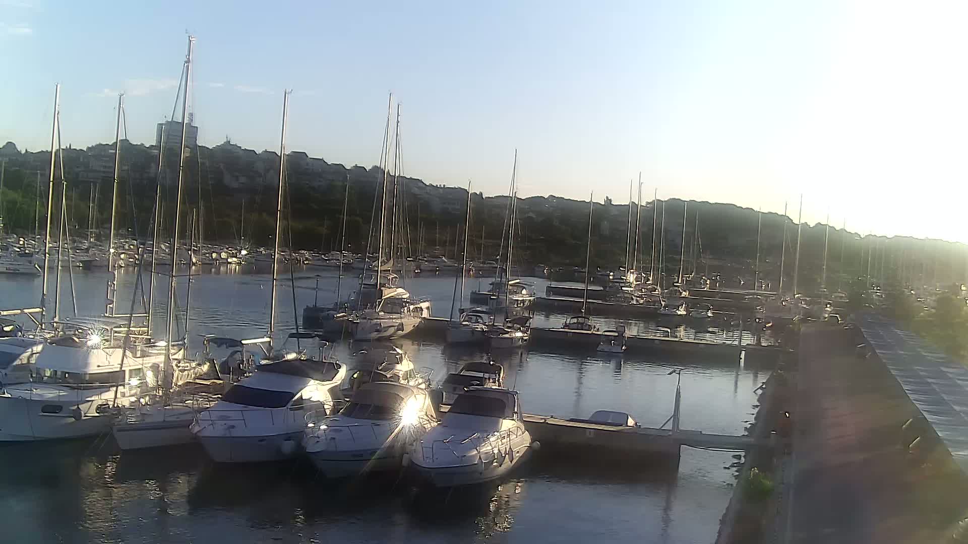 A marina filled with numerous sailboats and motorboats under a partly cloudy sky.