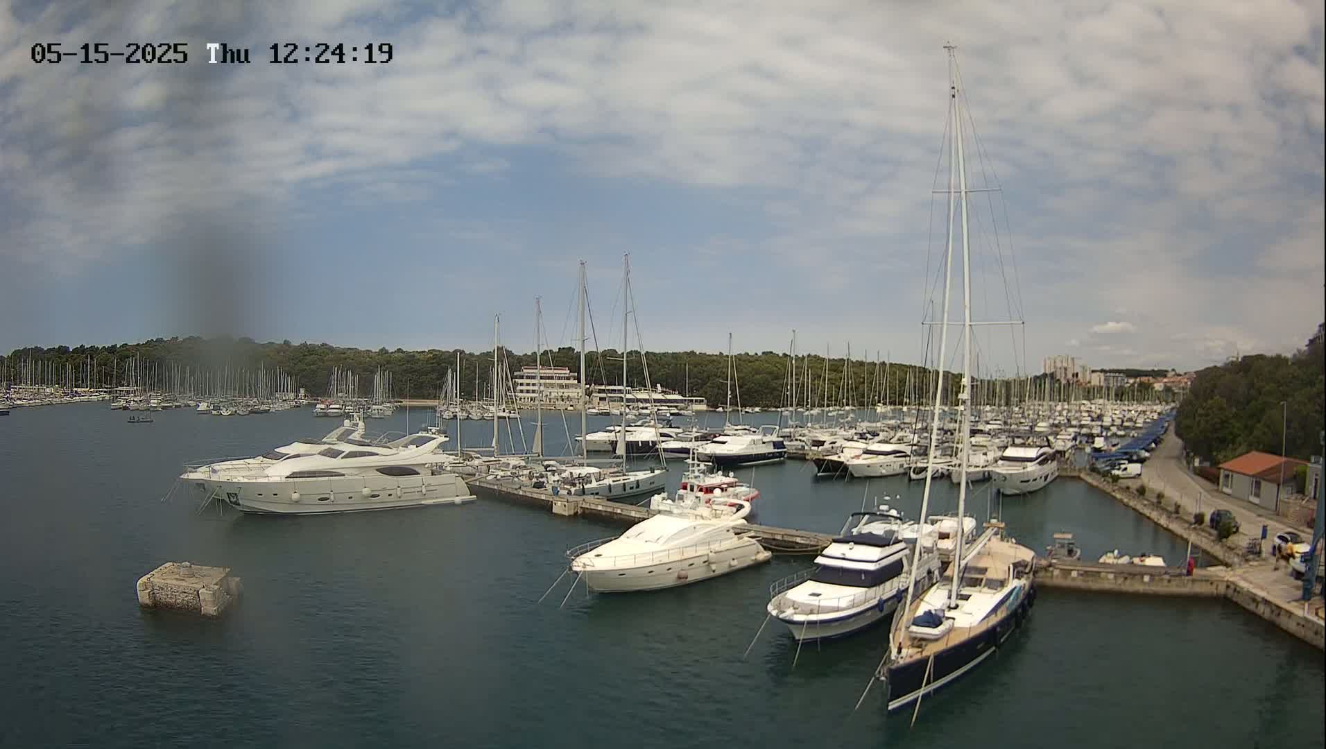 A marina filled with numerous yachts and sailboats under a partly cloudy sky.