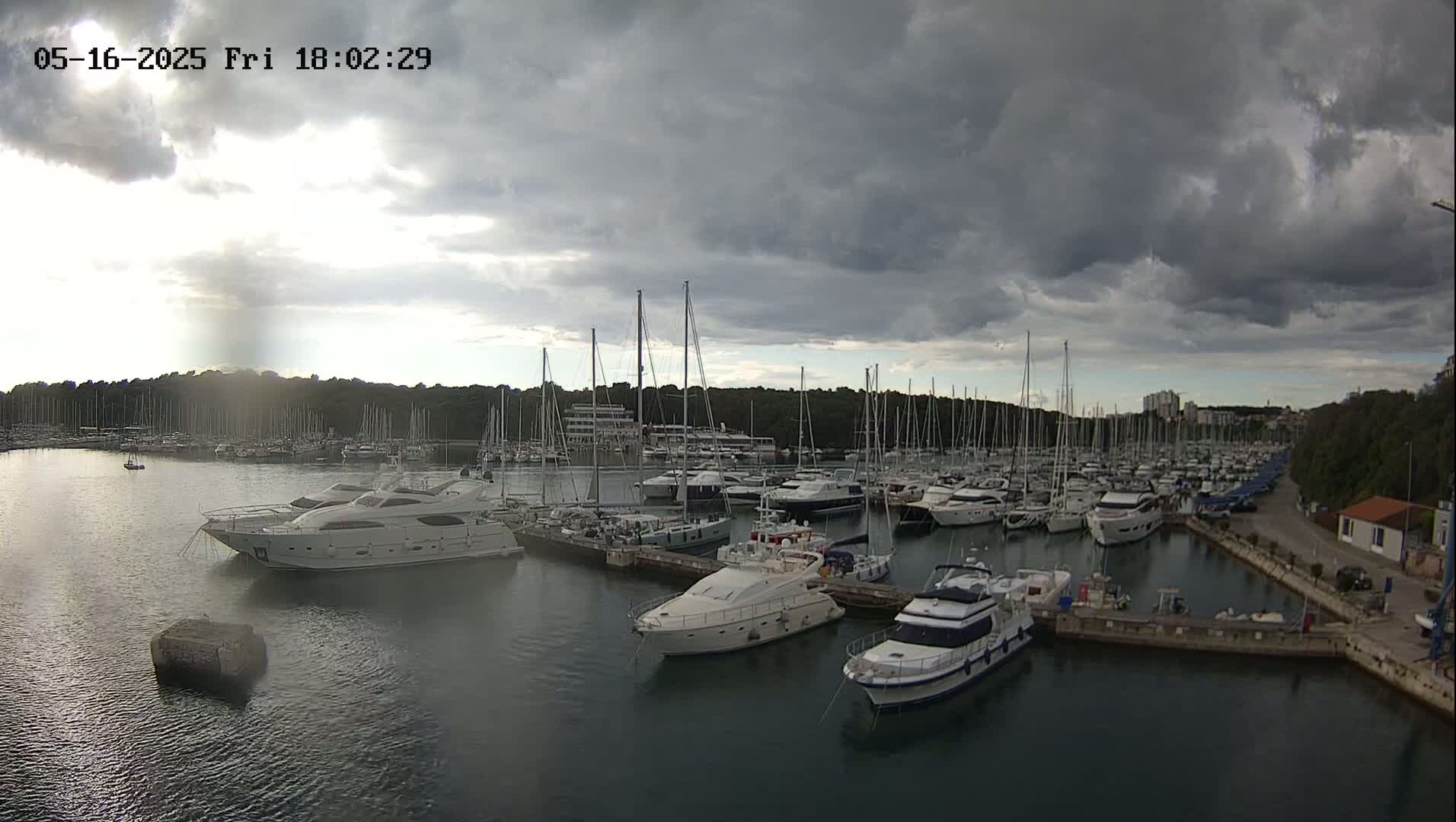 A marina filled with numerous yachts and sailboats under a cloudy sky.