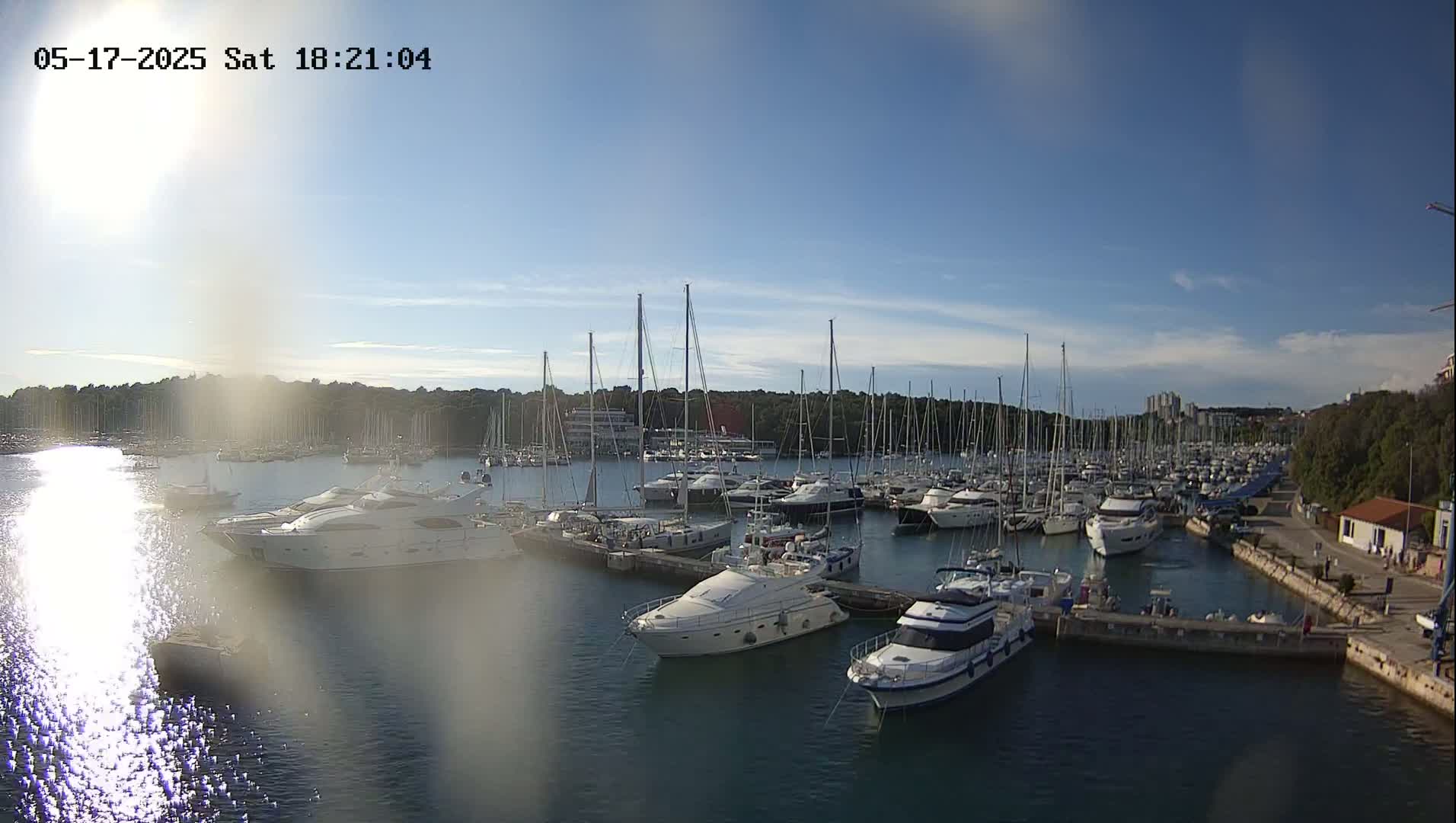 A marina filled with numerous yachts and sailboats under a mostly clear, sunny sky.