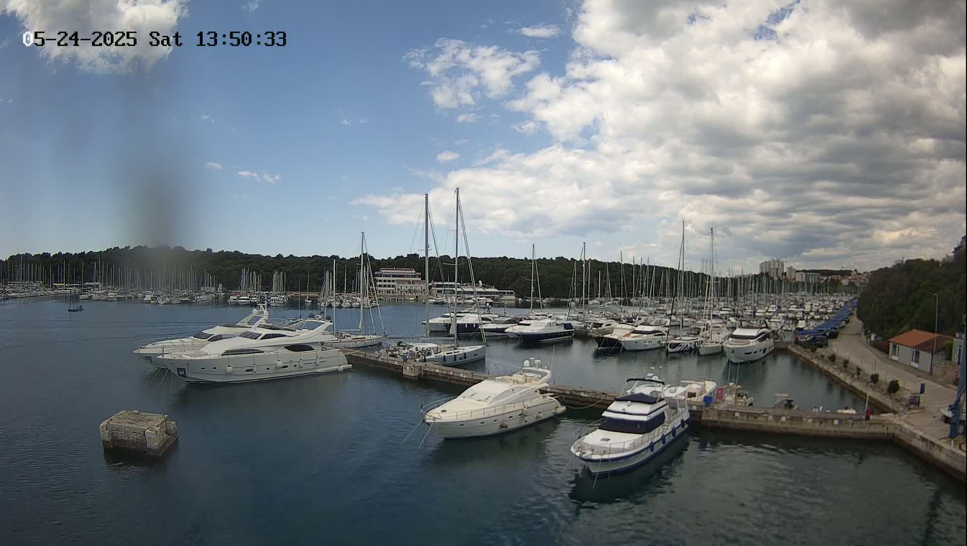 A marina filled with numerous sailboats and motor yachts under a partly cloudy sky.
