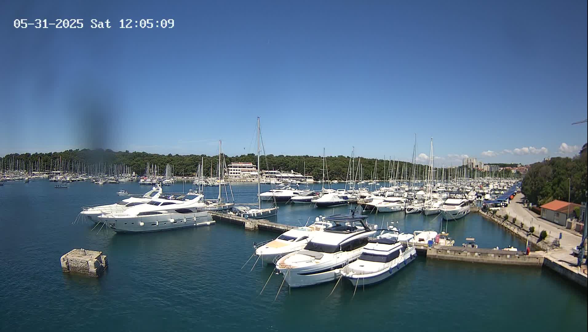 A marina filled with numerous yachts and sailboats is seen on a sunny day.