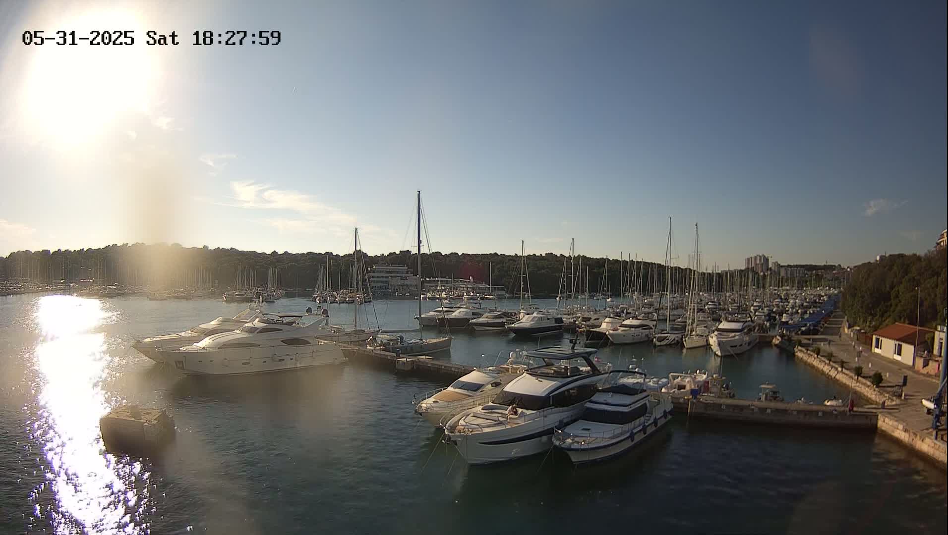 Many yachts and sailboats are moored in a marina on a sunny day.