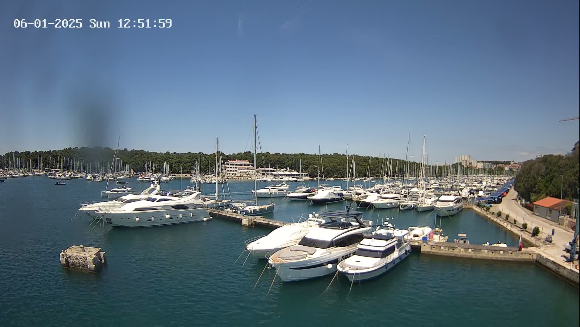 A marina filled with numerous yachts and sailboats on a sunny day.