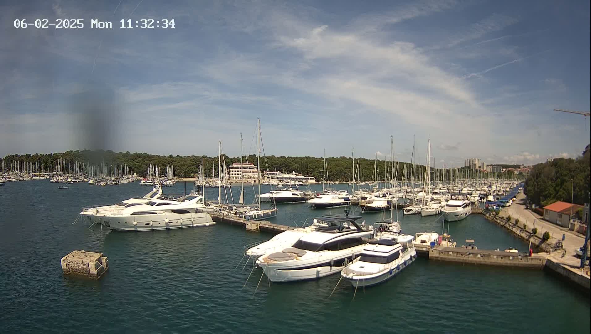 A marina filled with numerous yachts and sailboats under a partly cloudy sky.