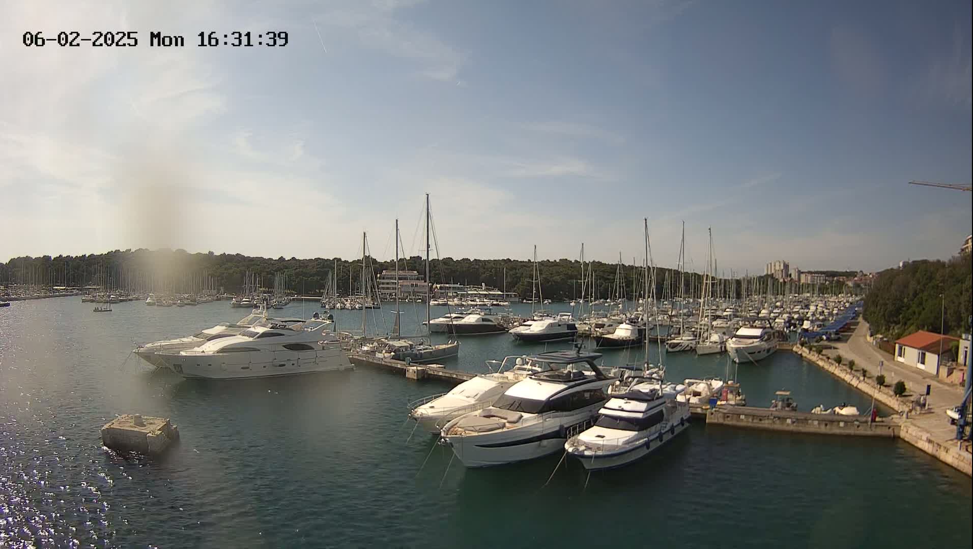 A marina filled with numerous yachts and sailboats under a mostly sunny sky.