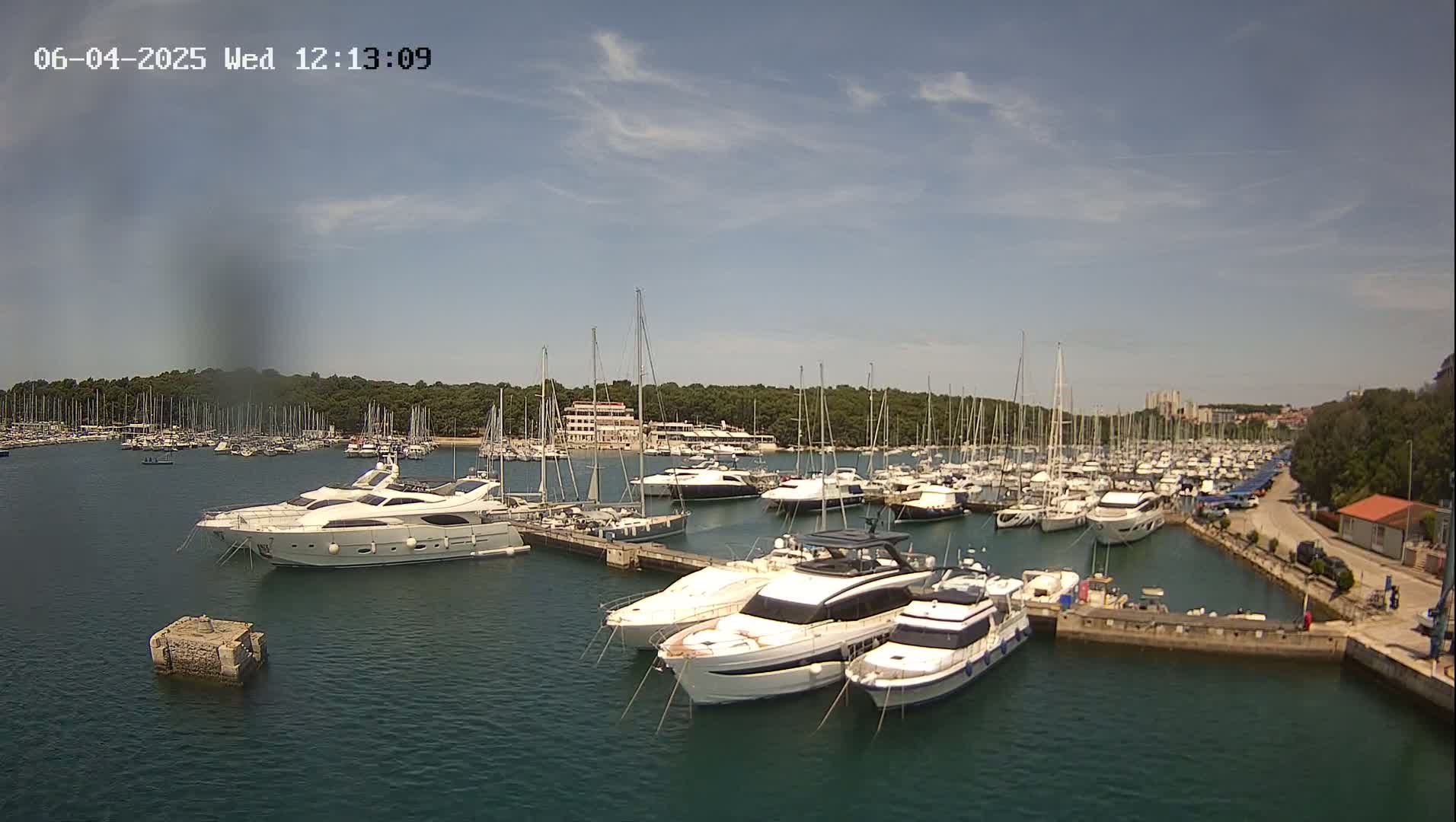 A marina filled with numerous yachts and sailboats on a sunny day with a mostly clear sky.