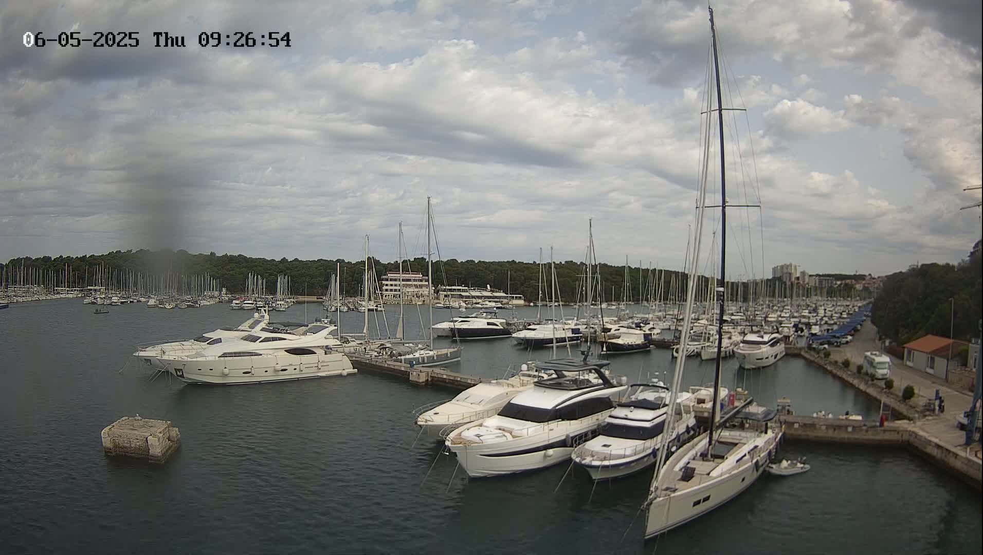 A marina filled with numerous yachts and sailboats under a partly cloudy sky.