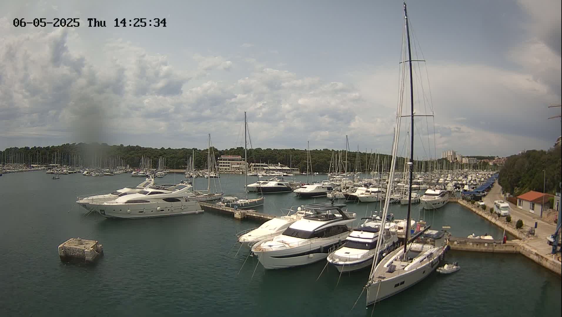 A marina filled with numerous yachts and sailboats under a partly cloudy sky.