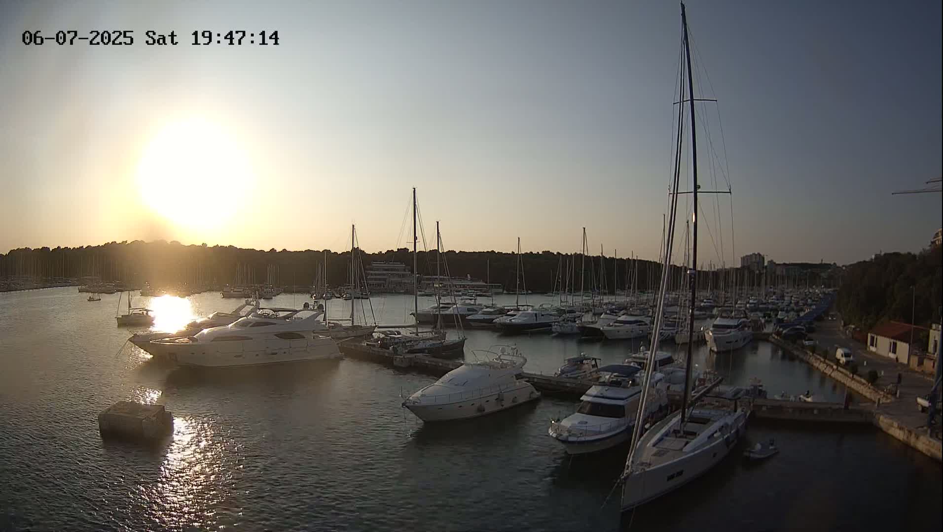 A marina filled with numerous boats and yachts at sunset under a clear sky.