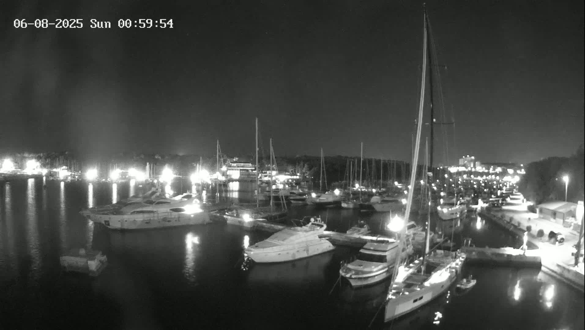 A marina filled with yachts and sailboats at night under a clear, dark sky.