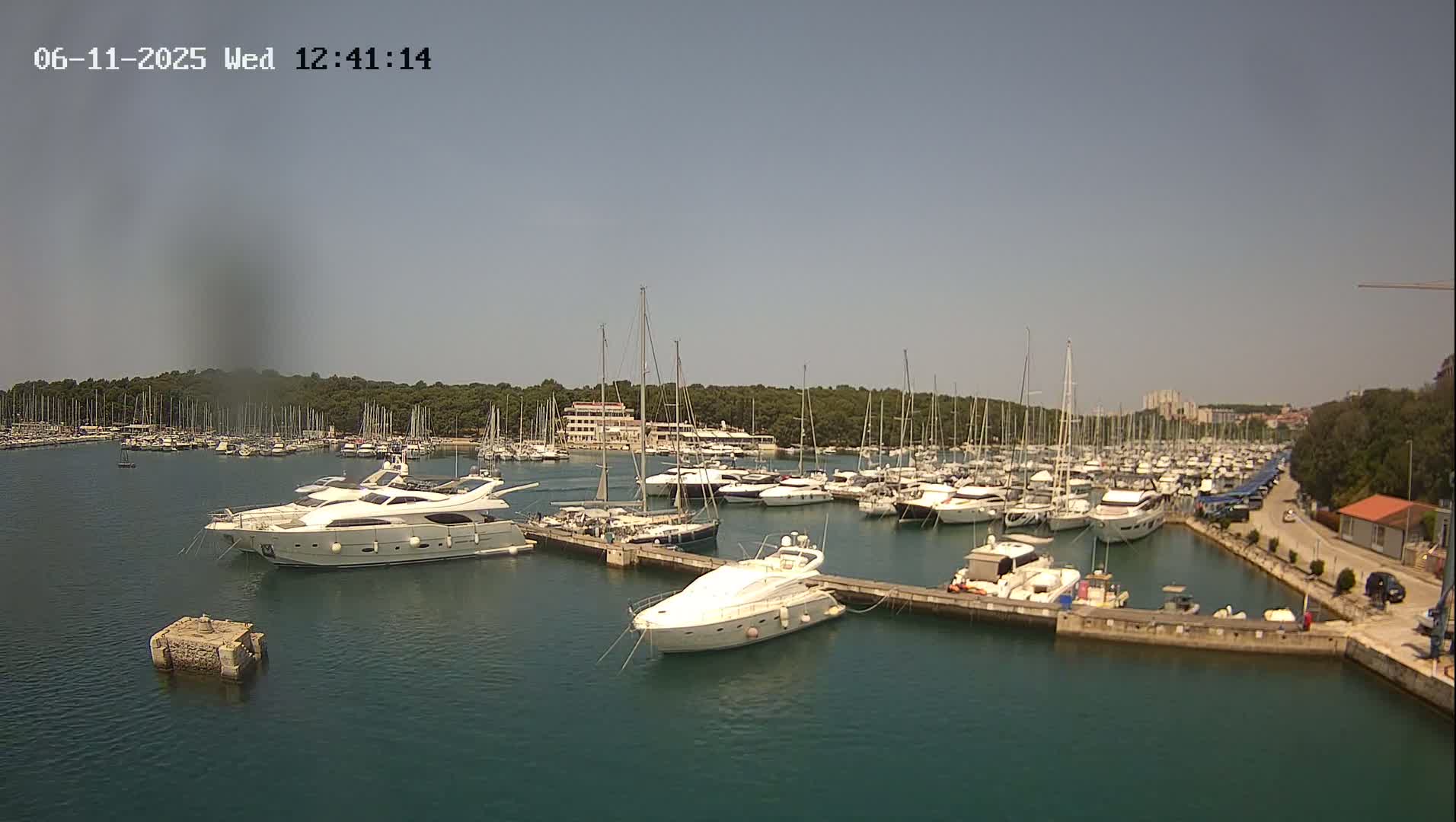 A marina filled with numerous sailboats and motor yachts on a sunny day.