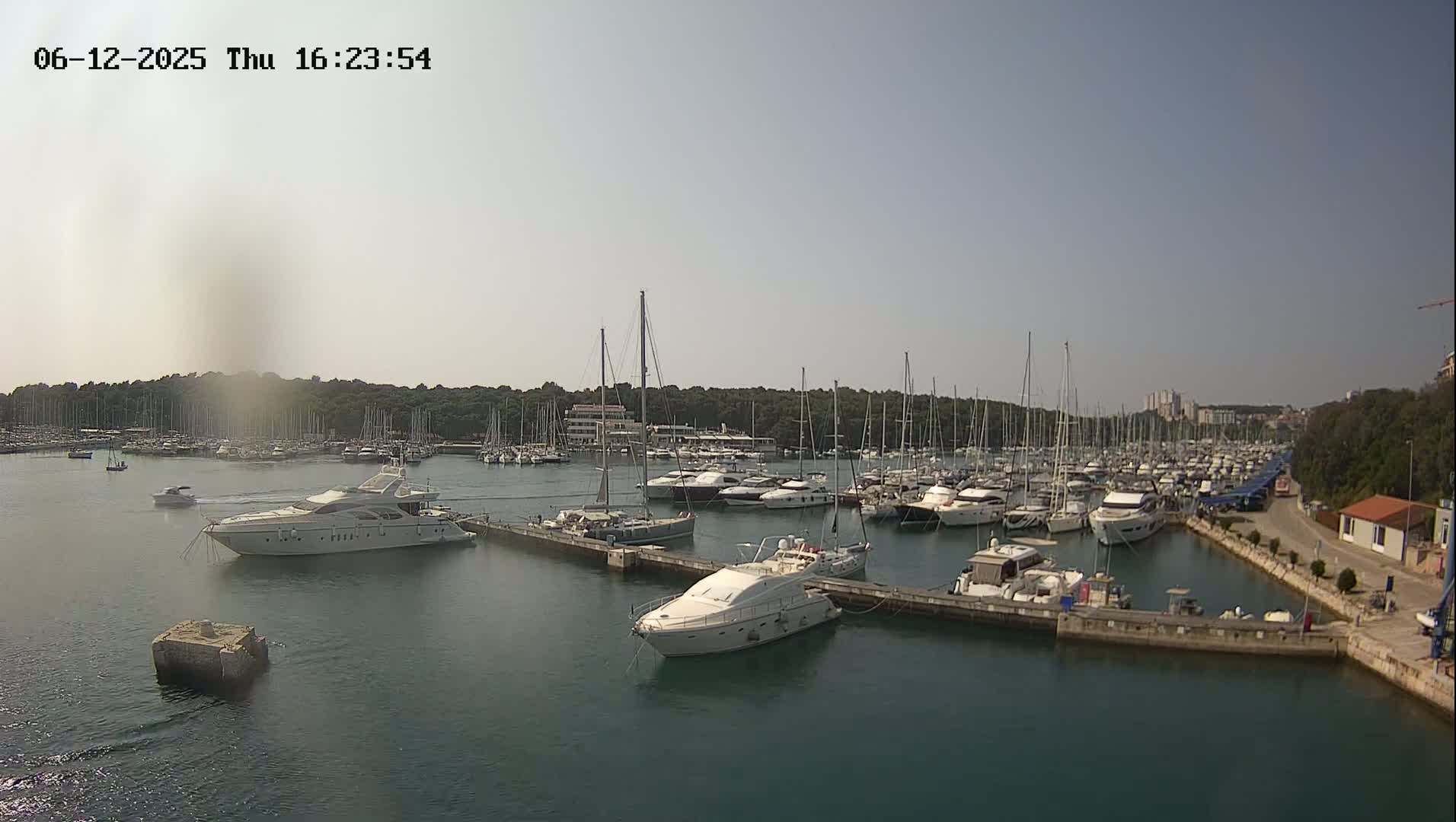 A marina filled with numerous sailboats and motor yachts on a sunny day.