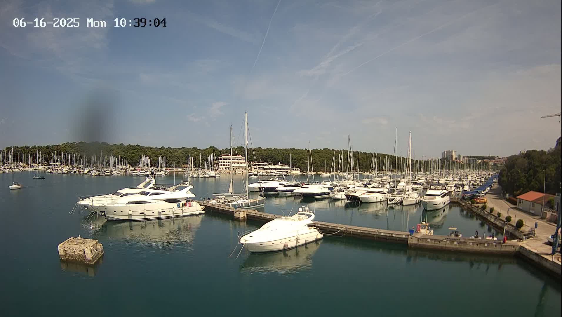 A marina filled with numerous yachts and sailboats under a mostly sunny sky.