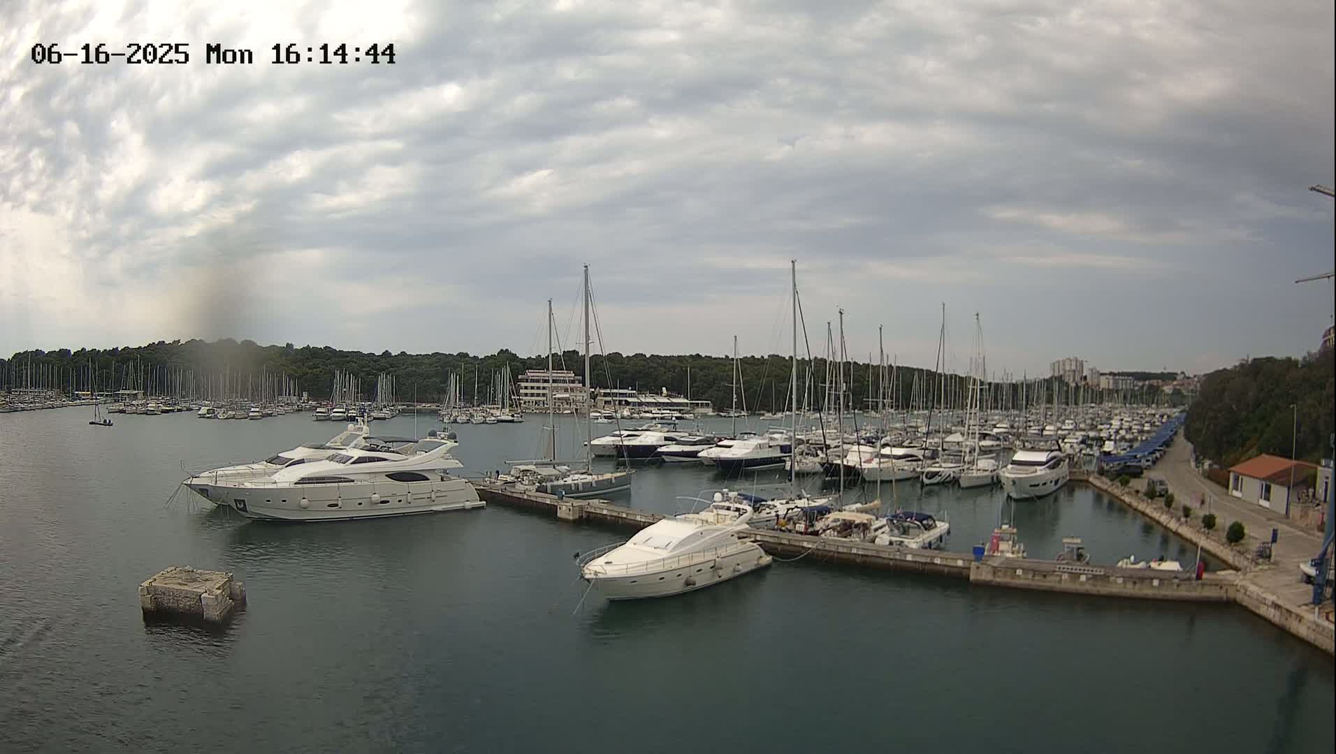 A marina filled with numerous sailboats and motor yachts under a cloudy sky.