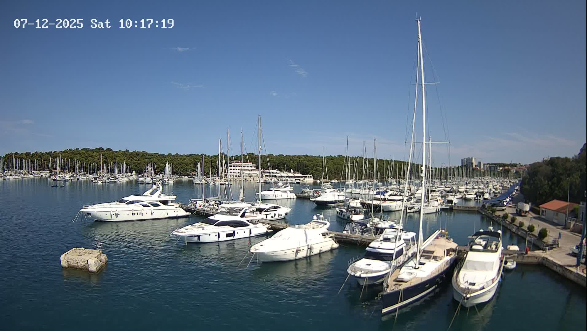 Many yachts and sailboats are docked in a marina on a sunny day.