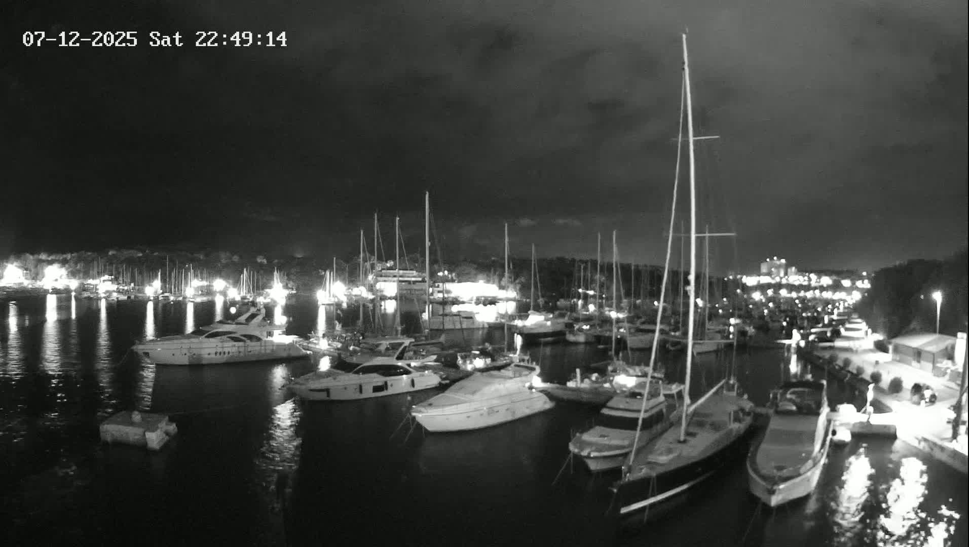 Many yachts and sailboats are docked in a marina on a sunny day.