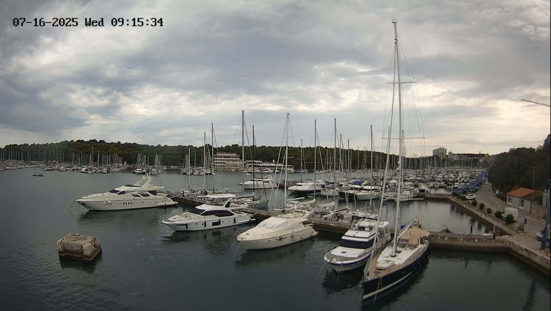 A marina filled with numerous yachts and sailboats under a cloudy sky.