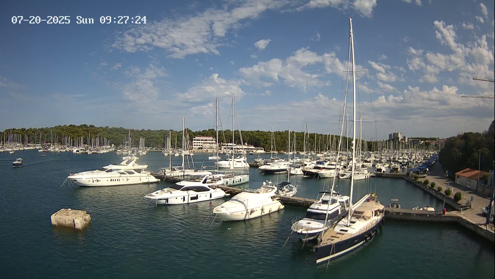 A marina filled with numerous yachts and sailboats under a partly cloudy sky.