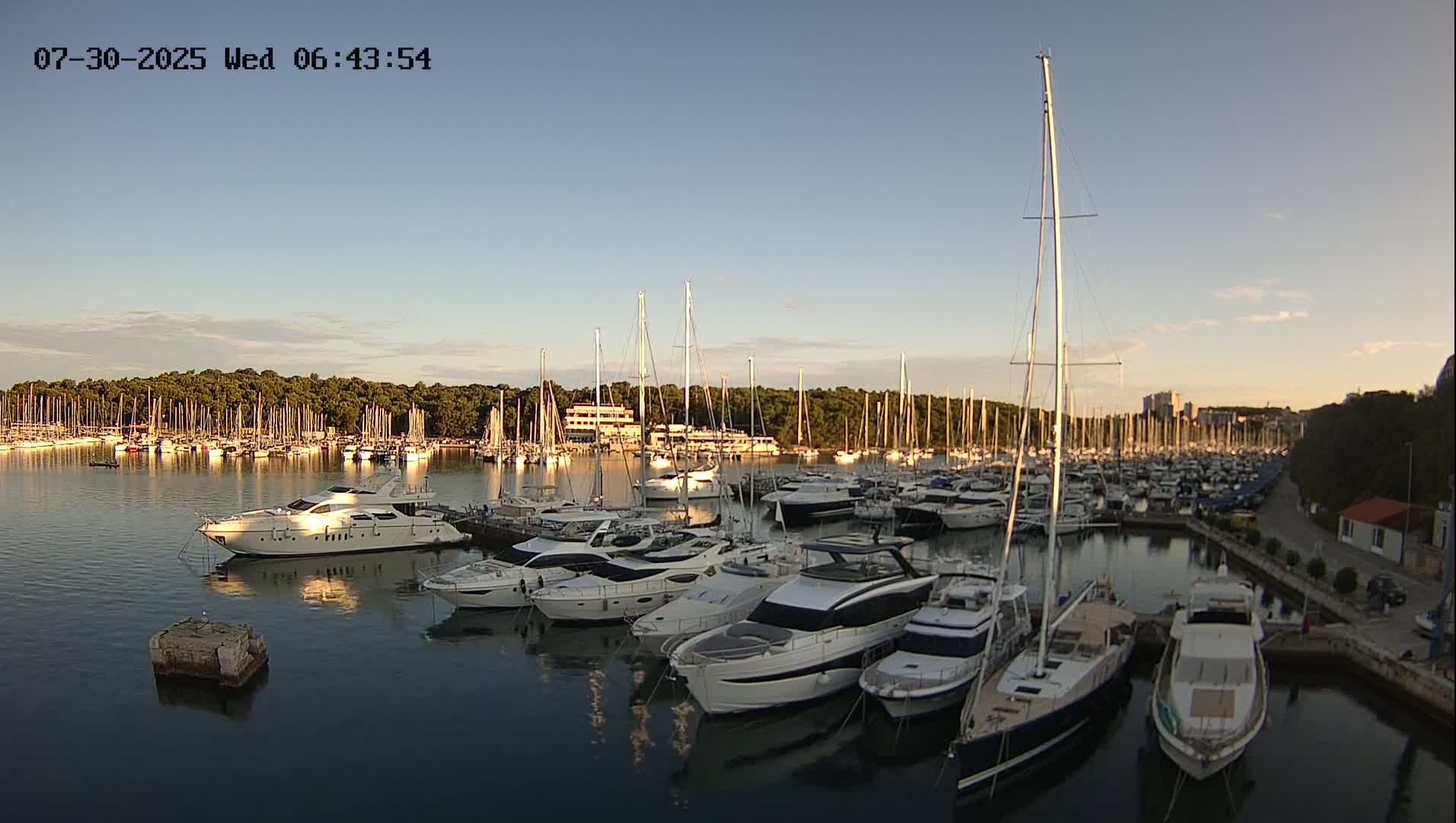 A marina filled with numerous yachts and sailboats under a partly cloudy sky.