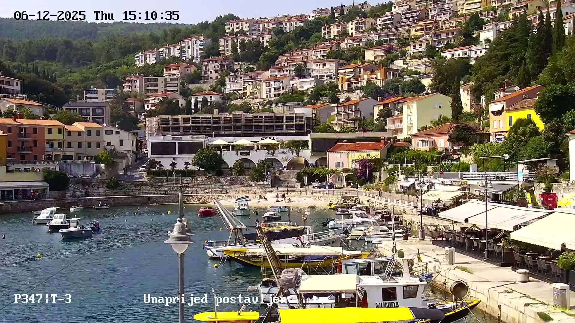 A harbor filled with boats sits below a hillside of closely packed buildings on a sunny day.