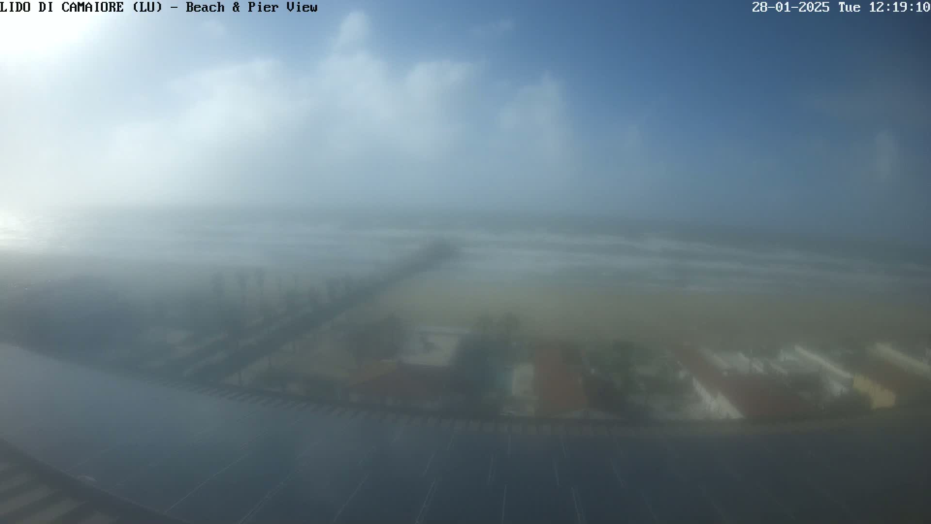 A hazy, foggy view of a beach, pier, and buildings from an elevated vantage point.
