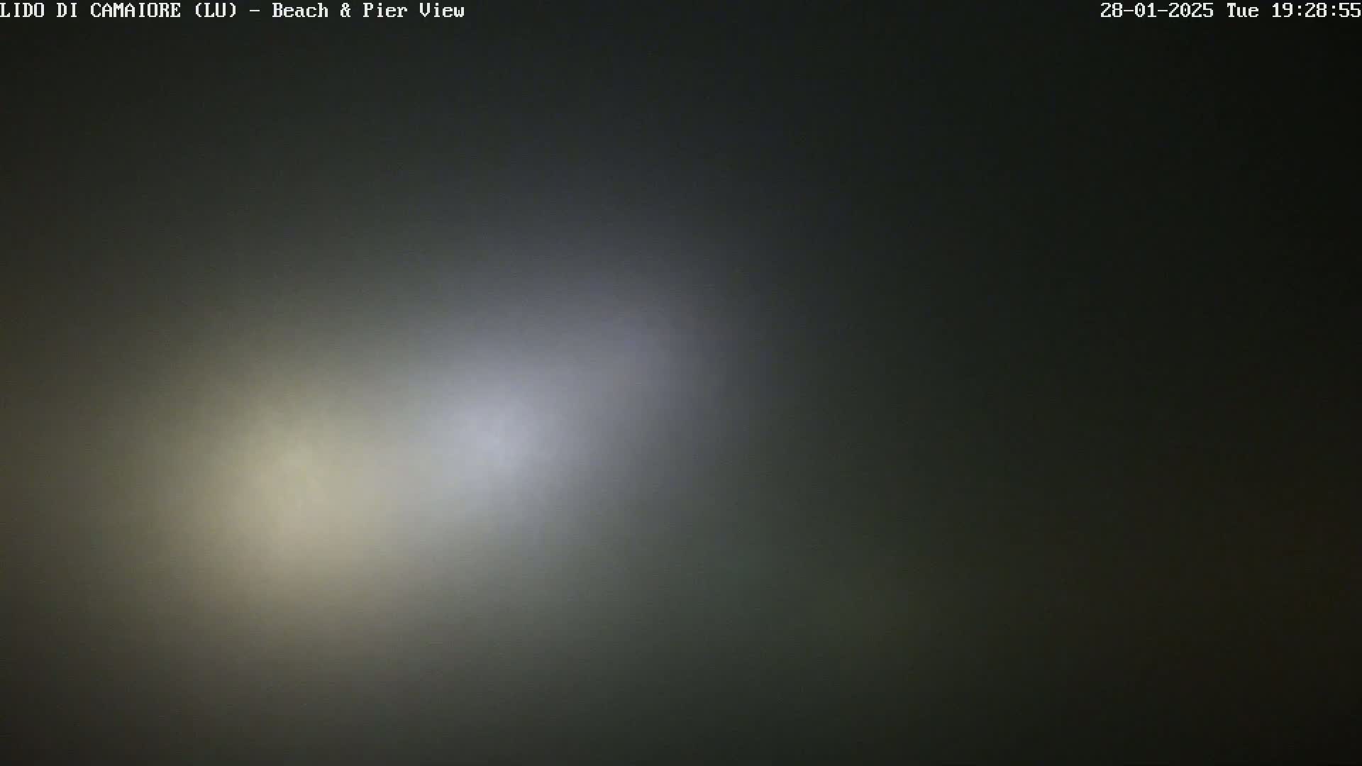 Two bright lights are visible through a thick fog at night.