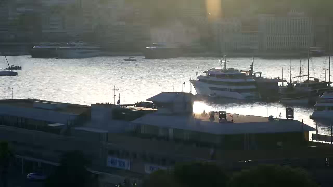 A harbor with several boats and a building is shown, bathed in the golden light of the setting sun.