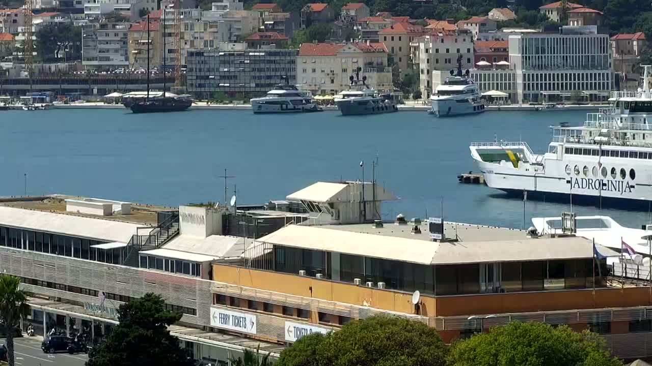 A harbor with several boats, yachts, and a ferry docked, on a sunny day.