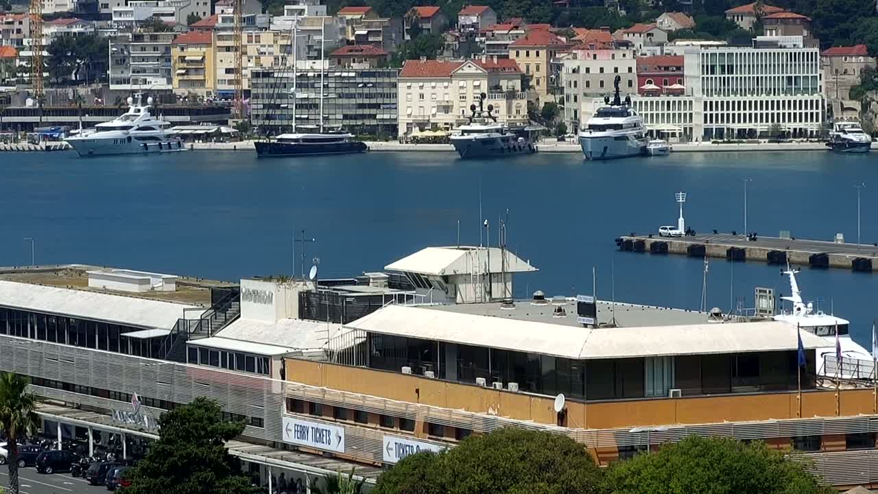 A harbor with several yachts and a ferry docked near a building, on a sunny day.