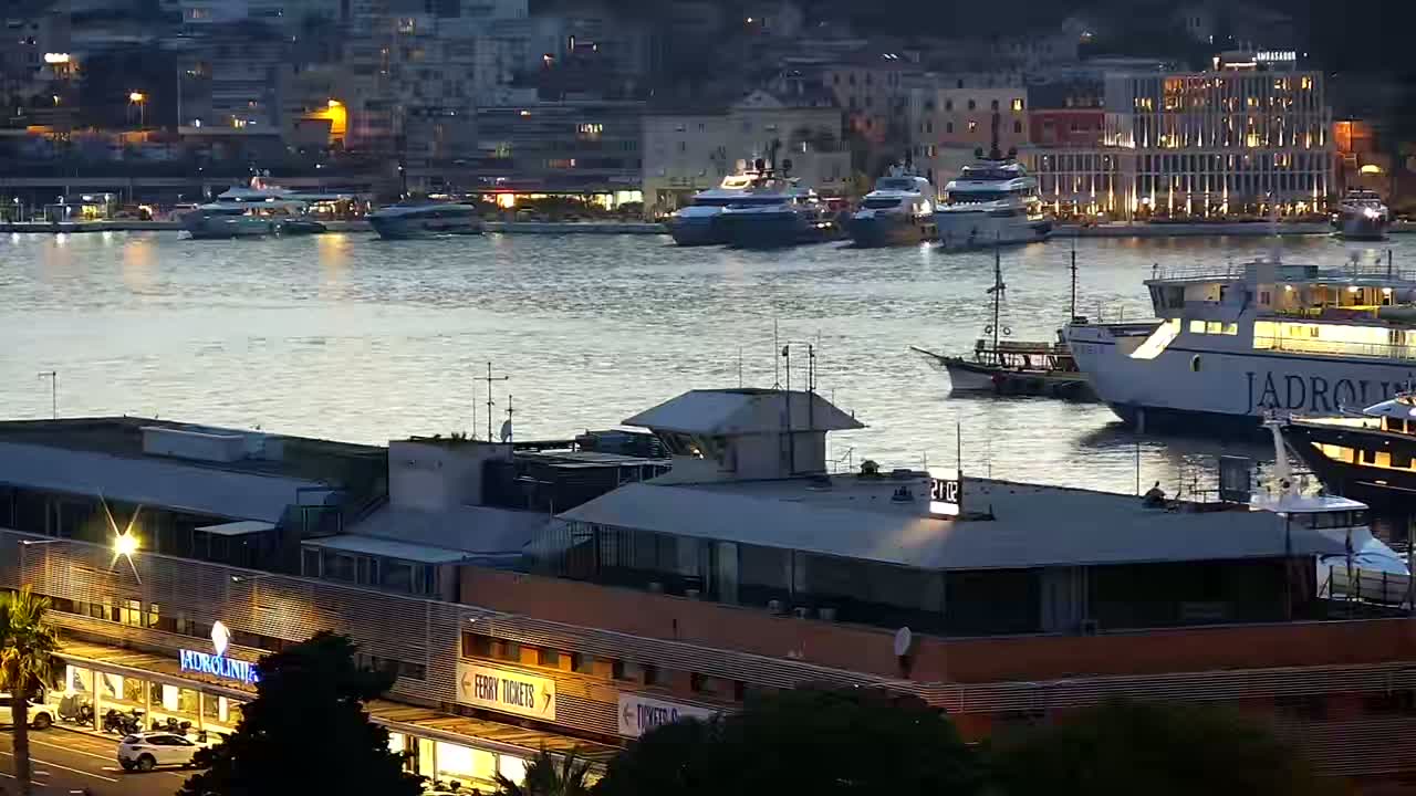 A large ferry is docked at a harbor filled with various boats and yachts on a sunny day.