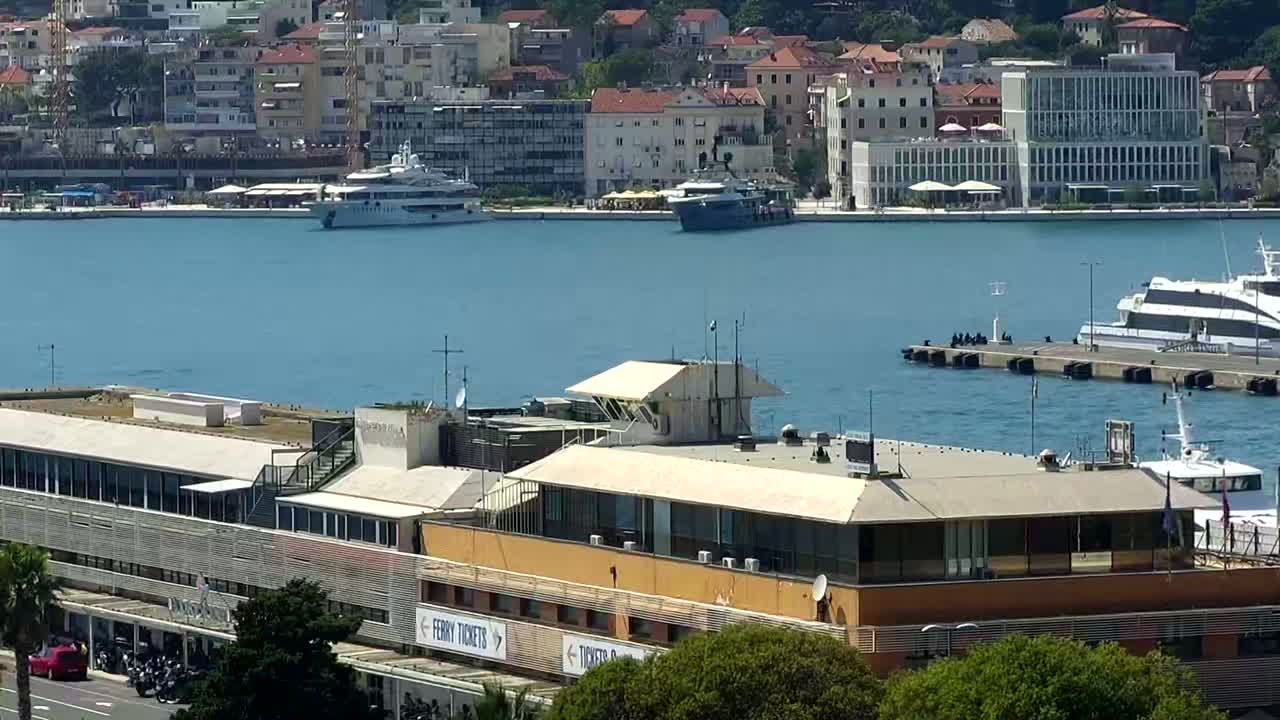 A harbor with several boats and a large building, under a sunny sky.