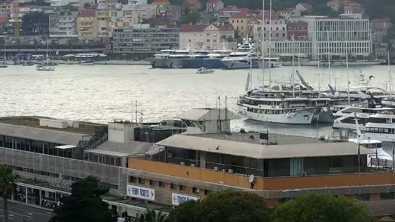 A harbor filled with numerous yachts and boats under a somewhat overcast sky, with a modern building in the foreground.